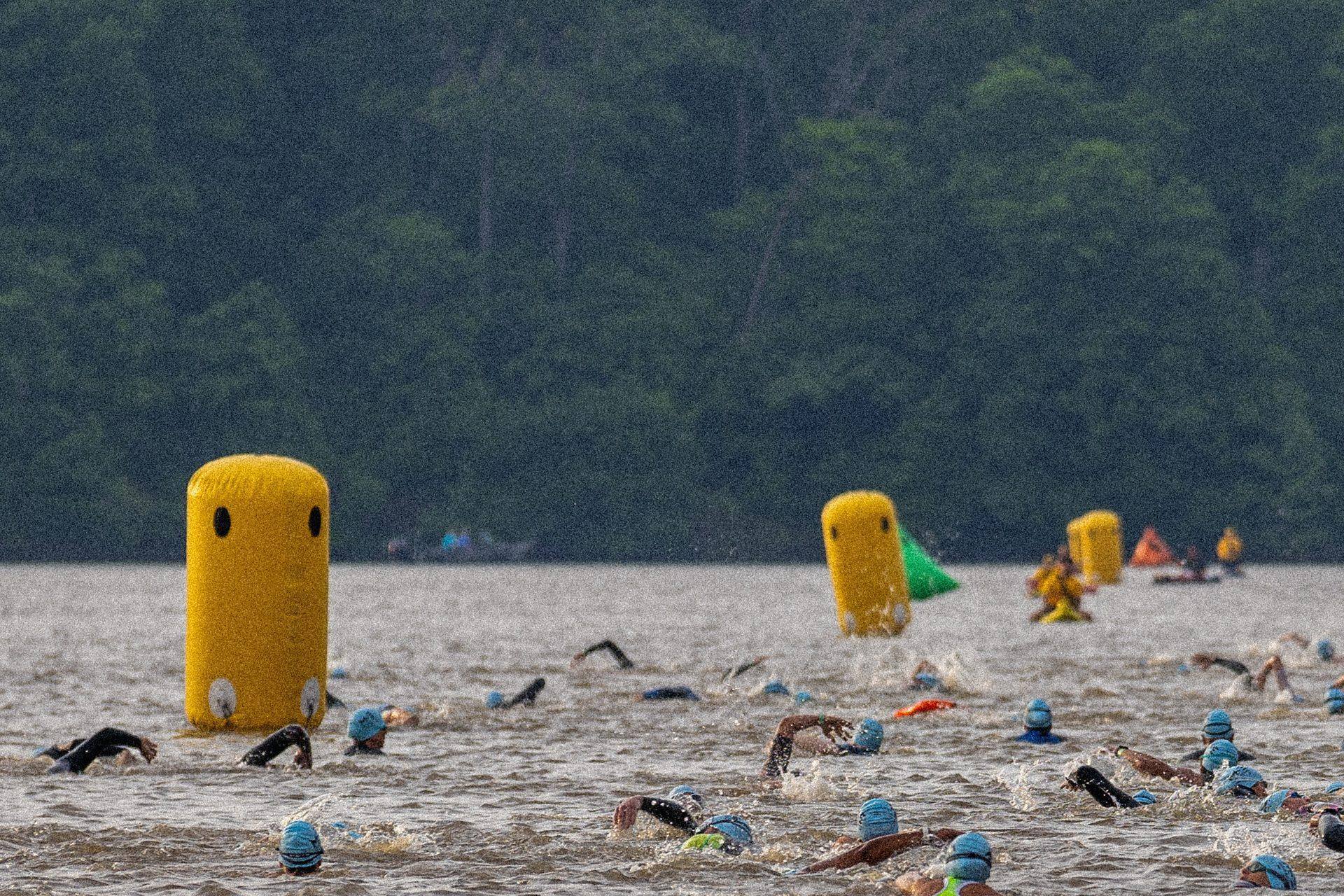 Open-water swimmers rounding a yellow buoy during a triathlon
